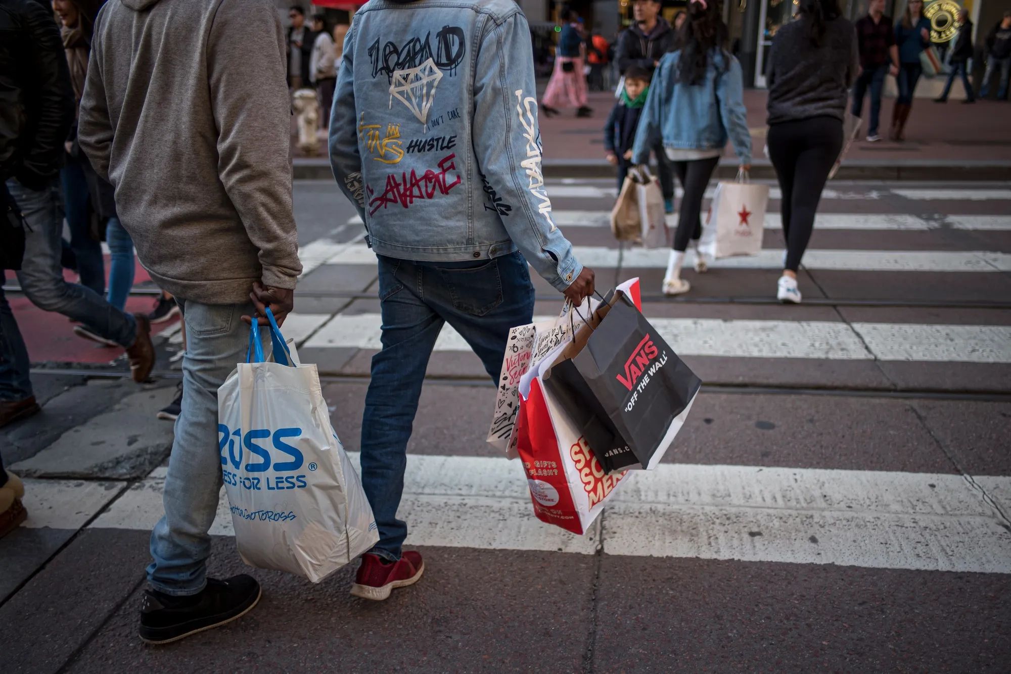 Pedestrians carry shopping bags.