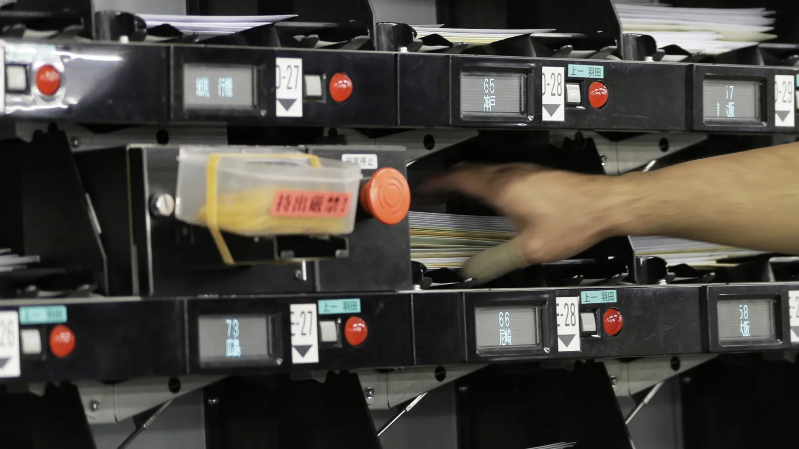An employee picks up mail from an automated sorting machine at a Japan Post Co. post office.

