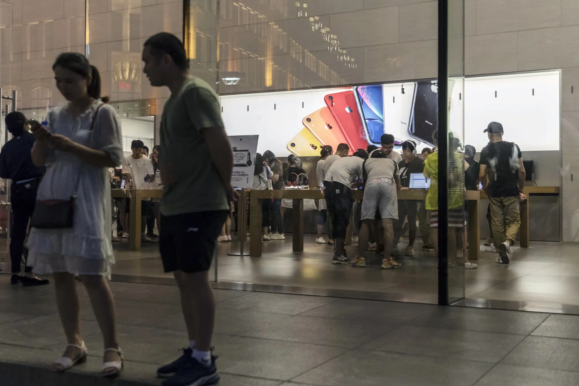 Pedestrians stand outside an Apple Inc. store in Shanghai.