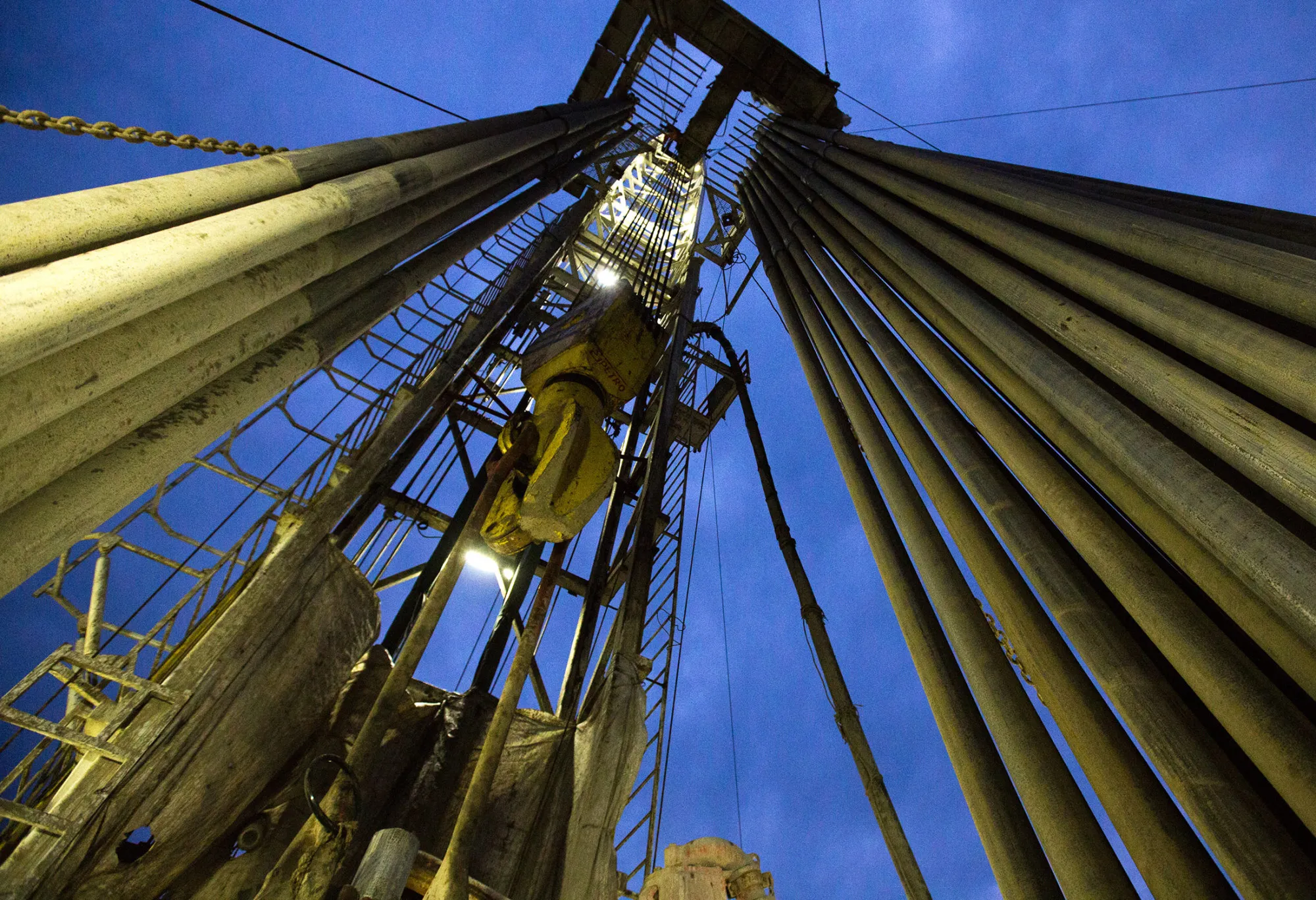 The travelling block hangs beside drill pipes on the derrick of a drill rig during oil drilling operations by Targin JSC, a unit of Sistema PJSFC, in an oilfield operated by Bashneft PAO near Ufa, Russia, on Thursday, Sept. 29, 2016. Bashneft distributes petroleum products and petrochemicals around the world and in Russia via filling stations.
