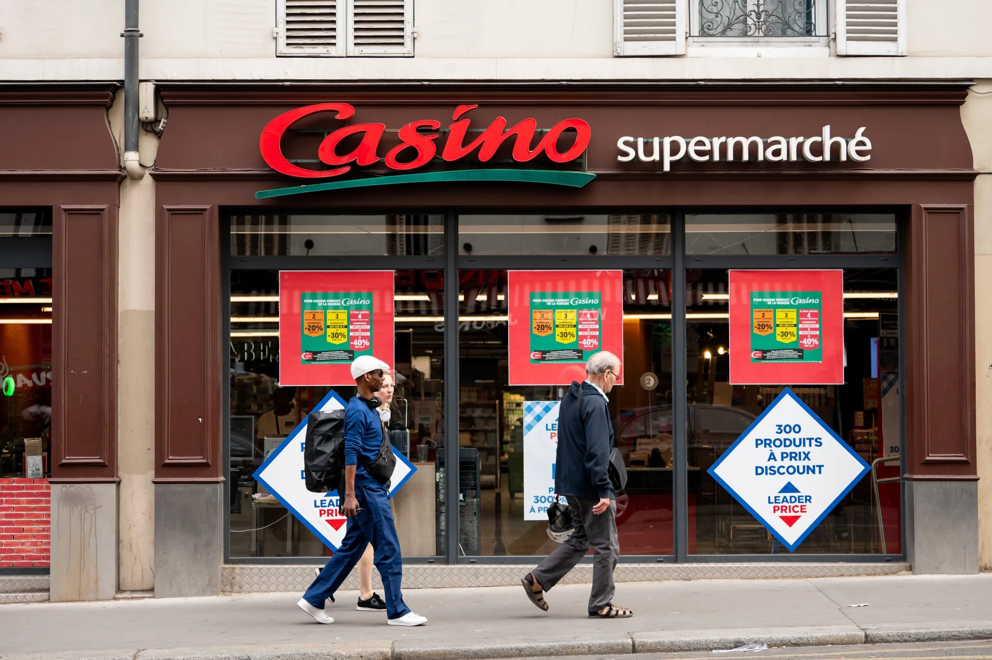 Pedestrians pass a Casino supermarket, operated by Casino Guichard-Perrachon SA, in Paris.