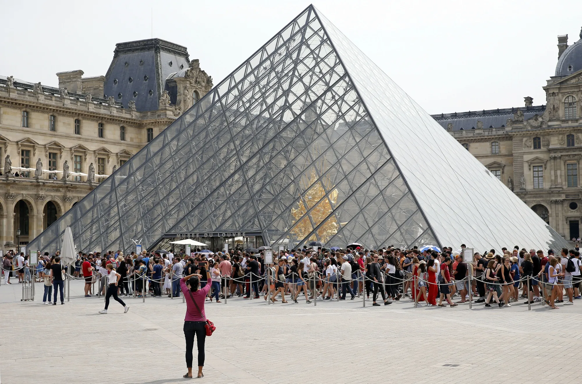 People queue in front of the Pyramid of the Louvre on July 05, 2018.