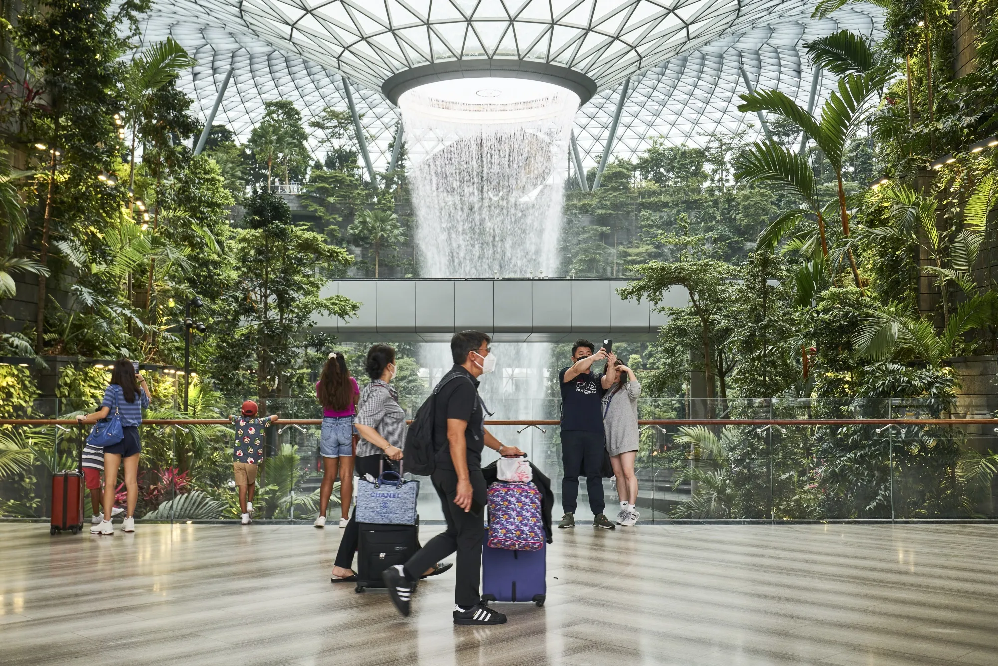 Travelers with baggage at Changi Airport.