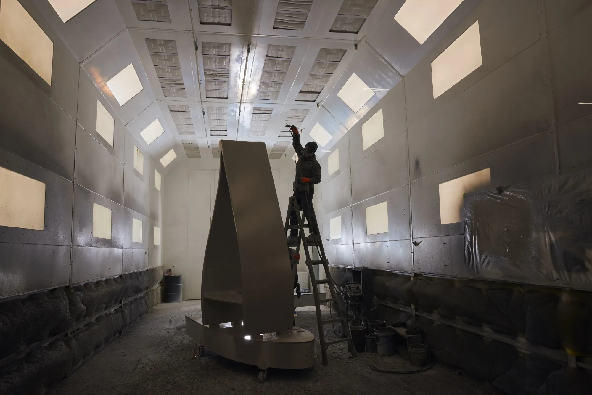 A worker applies paint to a section of a decommissioned wind turbine blade at a&nbsp;manufacturing facility in Avon, Ohio.