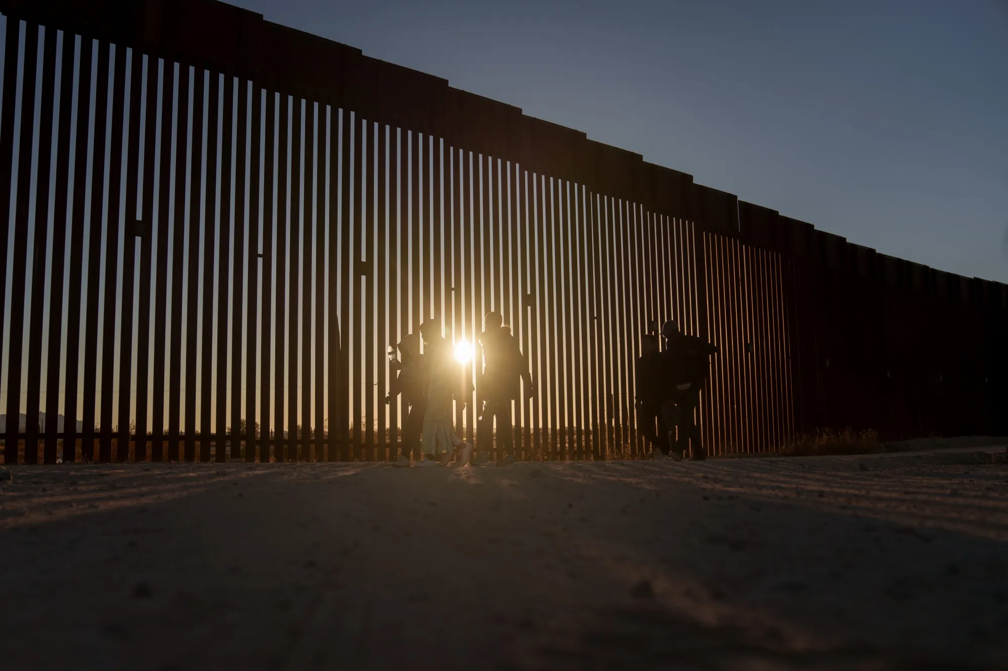 Migrants walk along the US-Mexico border fence in Lukeville, Arizona, US, on&nbsp;Dec. 12.