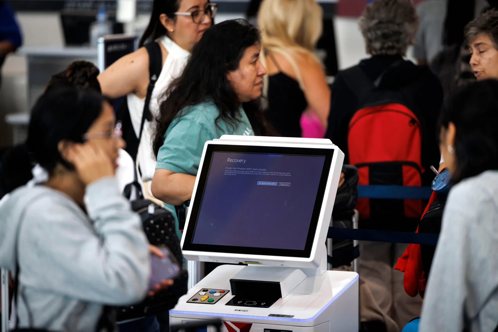 A display message&nbsp;reads "It looks like Windows didn't load correctly" as travelers wait in line at Ronald Reagan National Airport in Arlington, Virginia, on July 19.