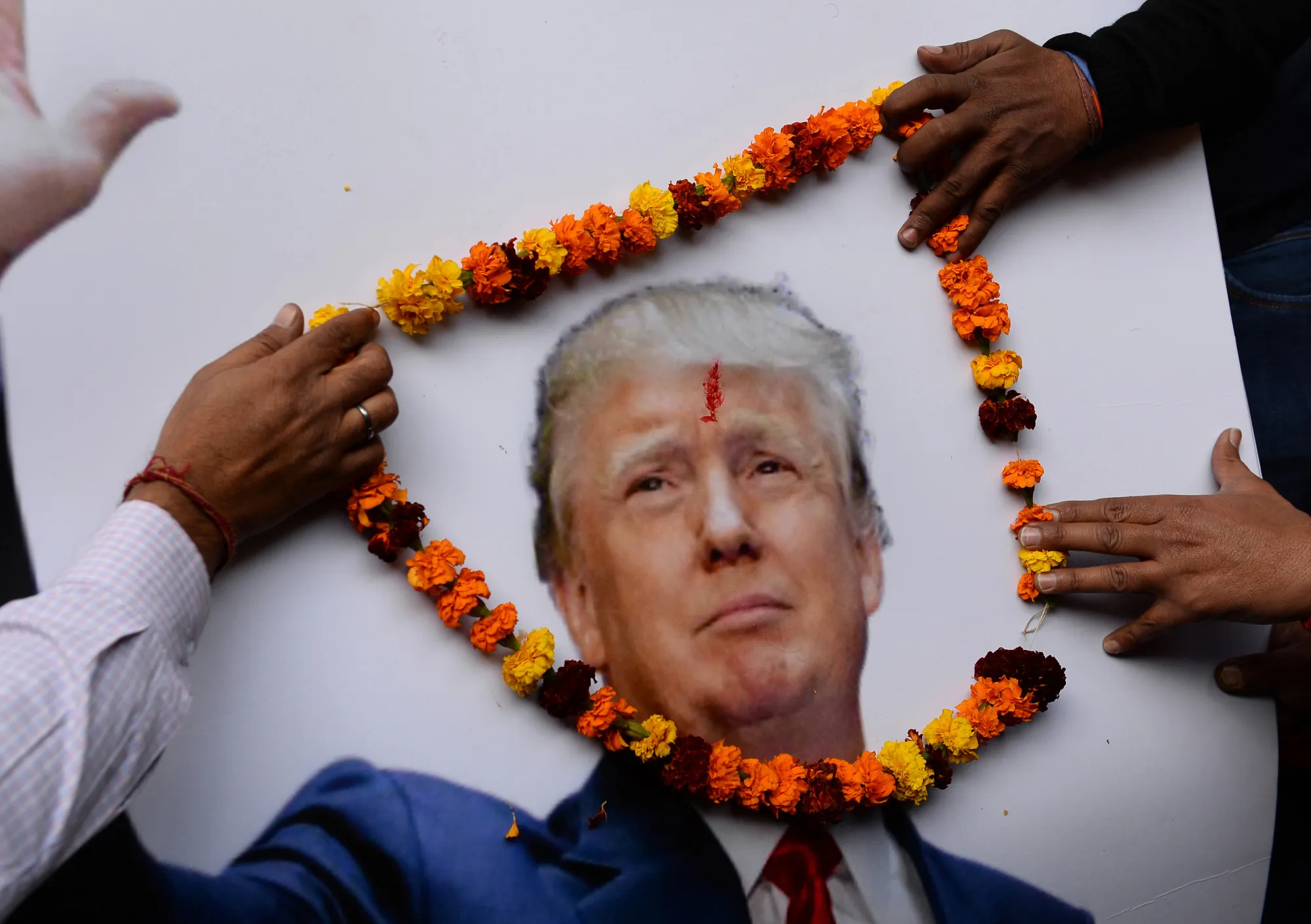 Hindu Sena party members garland a poster of Trump.