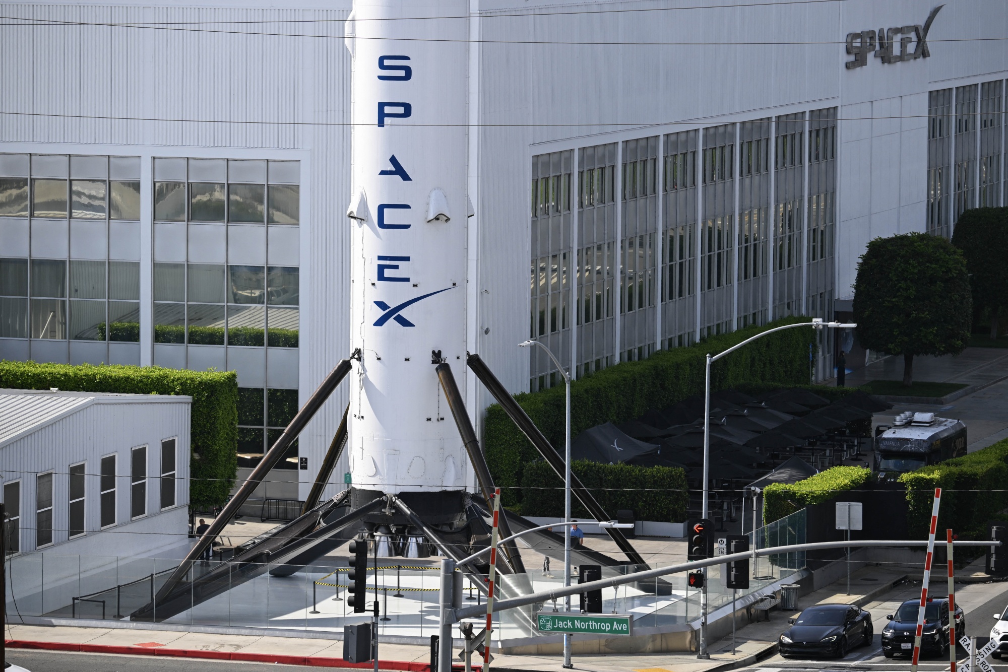 A Tesla electric vehicle drives past a SpaceX Falcon 9 rocket displayed outside a Space Exploration Technologies Corp. facility in Hawthorne, California, on June 8, 2026. SpaceX on June 5 signed a blockbuster cloud computing agreement under which Google will pay the Elon Musk-founded rocket company $920 million per month for access to a massive cluster of AI chips, according to a disclosure in its initial public offering filing. The deal, which will bulk up SpaceX's finances ahead of its IPO on June 12, covers a computing infrastructure of approximately 110,000 Nvidia GPUs -- the crucial hardware needed to power Google's AI models. (Photo by Patrick T. Fallon / AFP via Getty Images) Photographer: PATRICK T. FALLON/AFP