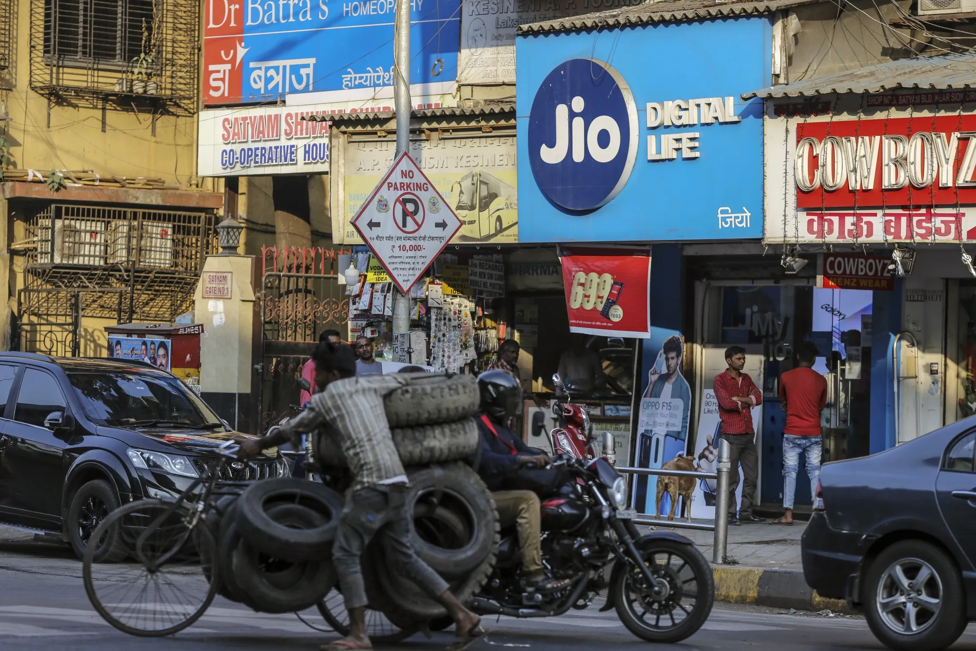 A worker transports tires past a stores in Mumbai, India.