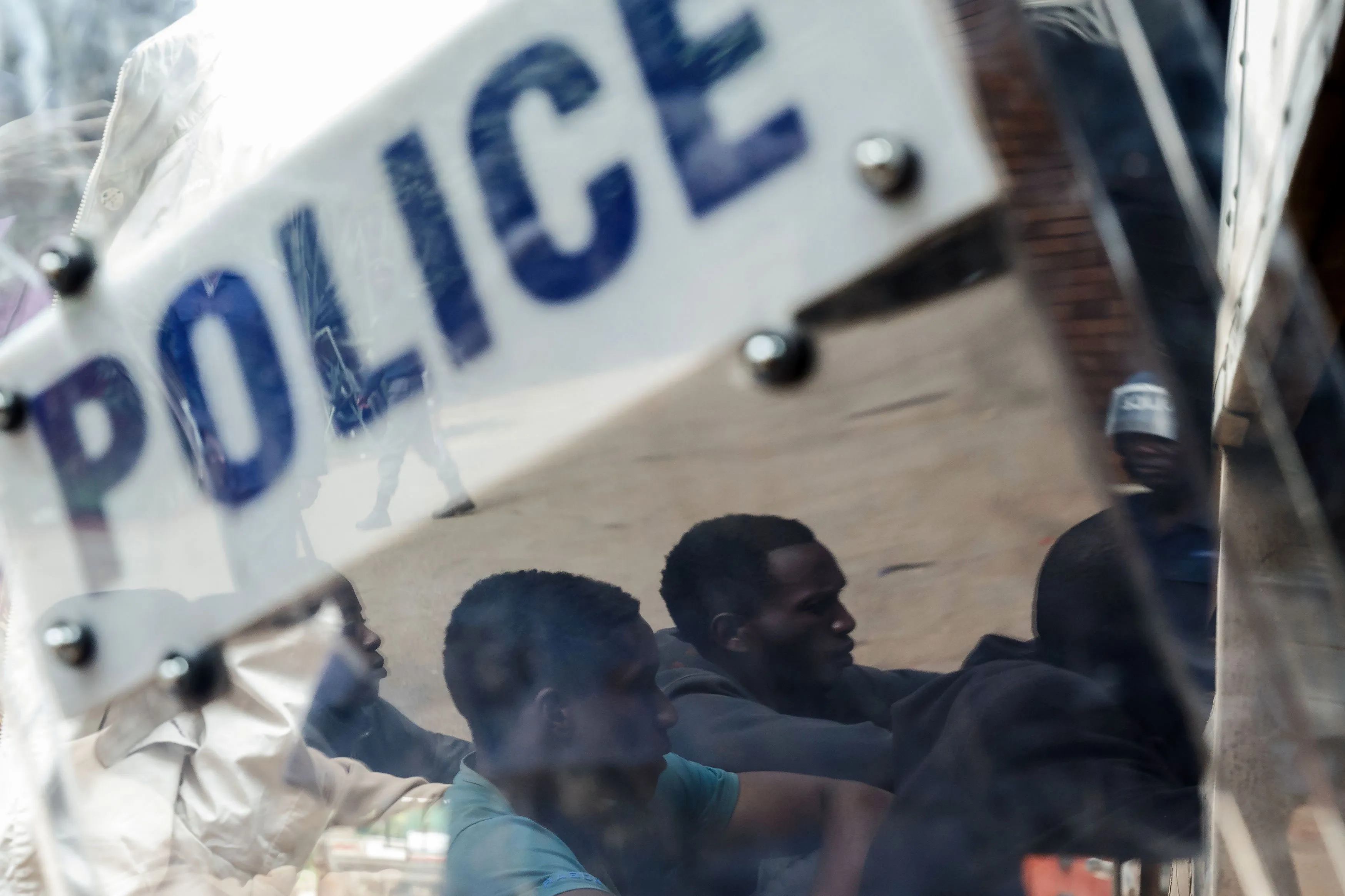 Zimbabwean anti-riot police forces watch men, arrested during violent protests triggered by a sudden rise in fuel prices, at&nbsp;their hearing at the Law Court in Harare.