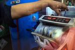 An employee counts U.S. dollar banknotes using a money-counting machine at a currency exchange store in Bukit Bintang in Kuala Lumpur, Malaysia, on Tuesday, August 25, 2015.
