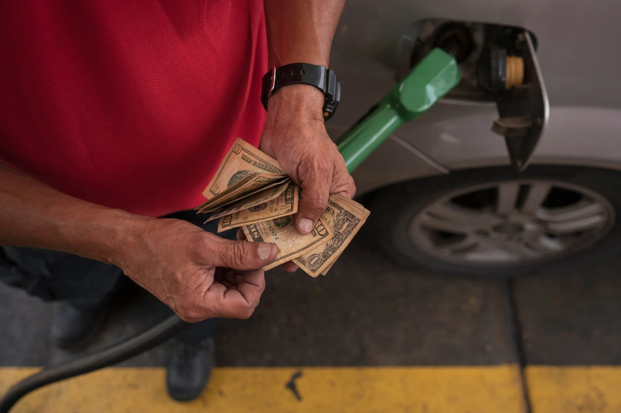 An attendant counts US dollar bills at a Petroleos de Venezuela (PDVSA) gas station in Caracas, Venezuela, on Dec. 17.