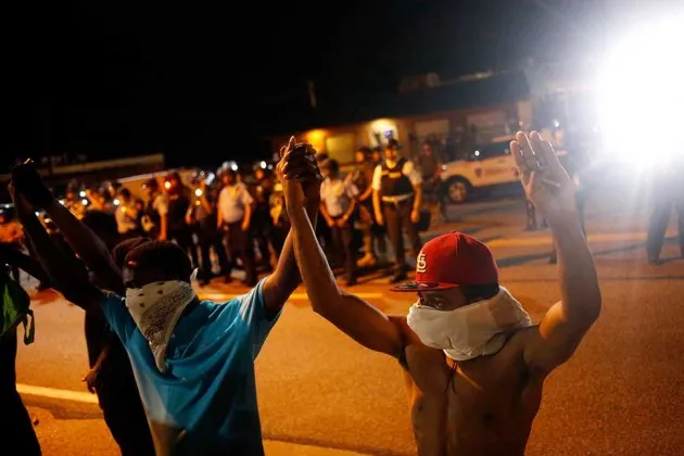 Protestors raising their hands above their heads in mock surrender  in Ferguson, Mo.