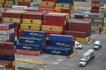 Trucks drive past shipping containers stacked at the Port of Houston.