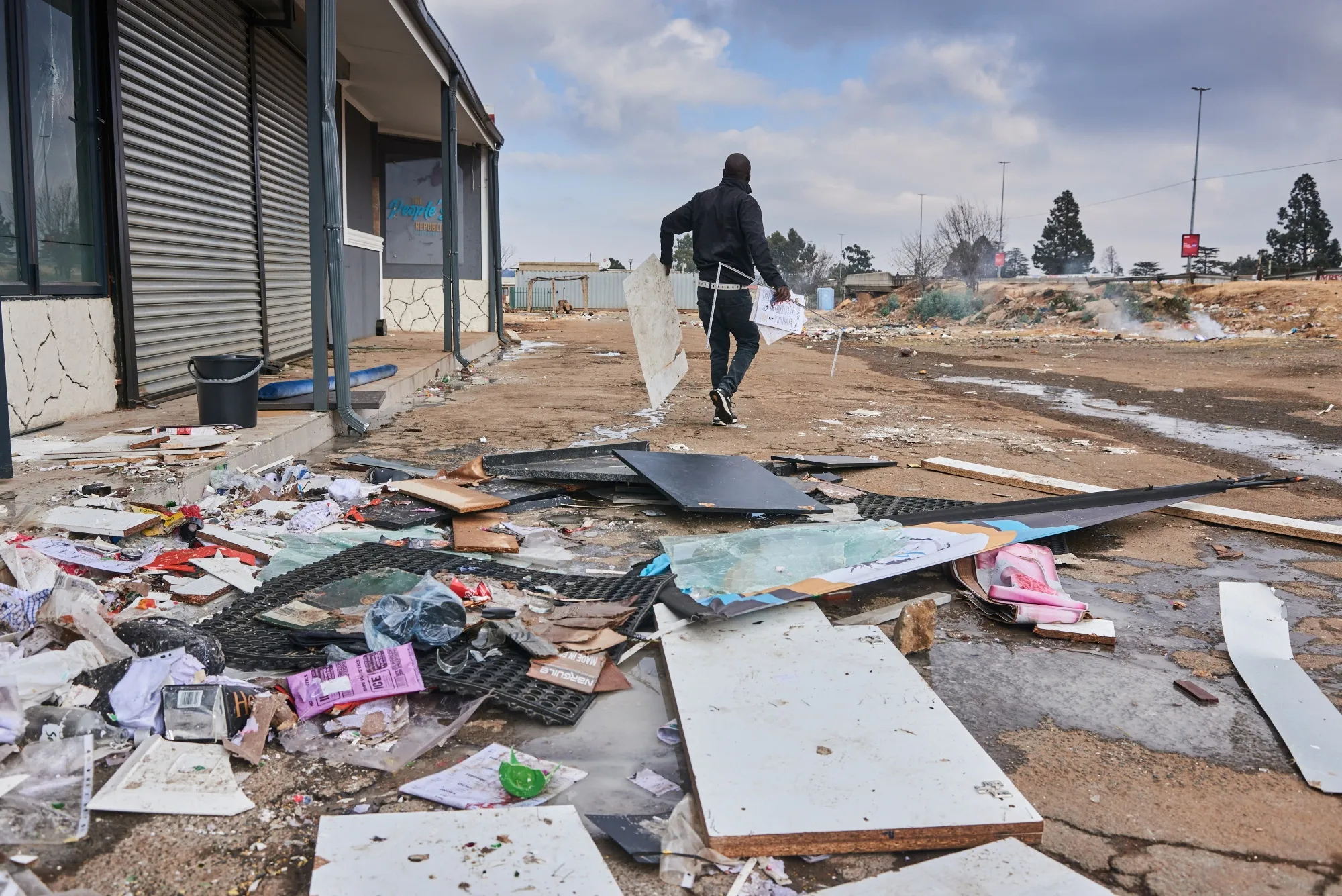 A resident clears debris after rioting in Soweto, South Africa.