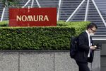 A pedestrian wearing a protective face mask walks past the Nomura Holdings Inc. signage outside its headquarters in Tokyo, Japan, on Monday, March 29, 2021. Nomura's warning of a "significant" potential loss from an unnamed U.S. client is related to the unwinding of trades by Bill Hwangs Archegos Capital Management, according to people familiar with the matter.