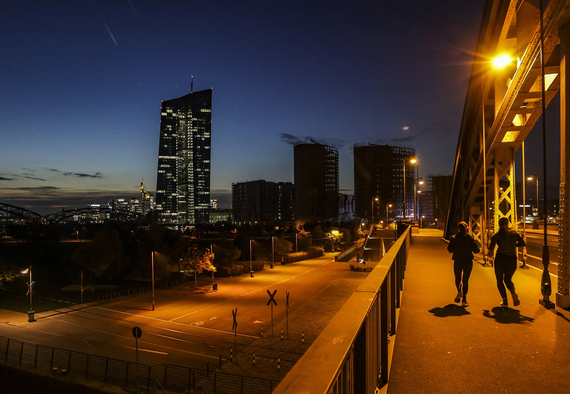Joggers run across a bridge close to ECB headquarters in Frankfurt.