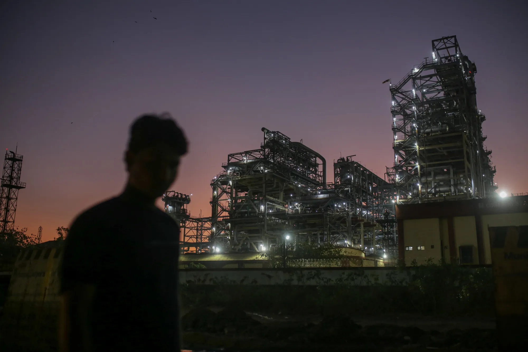 A pedestrian walks past an oil refinery&nbsp;in Mumbai, India.