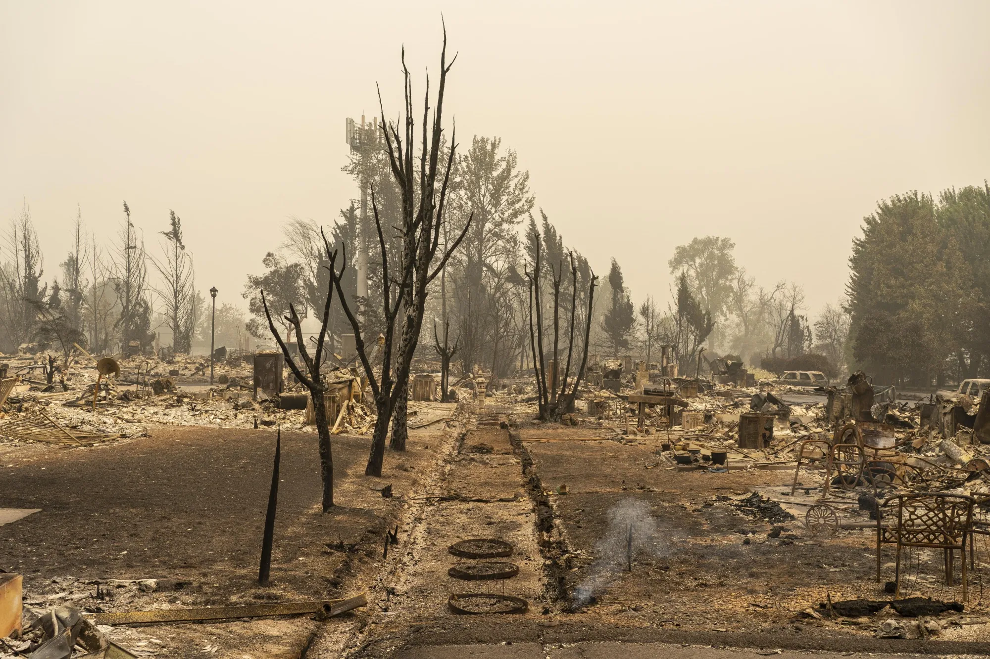 Smoke rises from the ground in a neighborhood destroyed by wildfire in Talent, Oregon in 2020.
