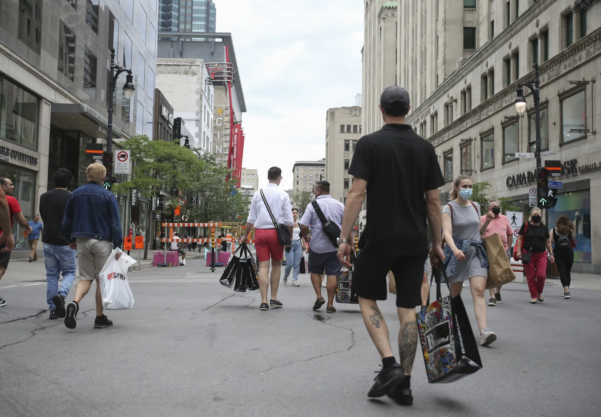 People carry shopping bags while walking on St. Catherine Street in Montreal.