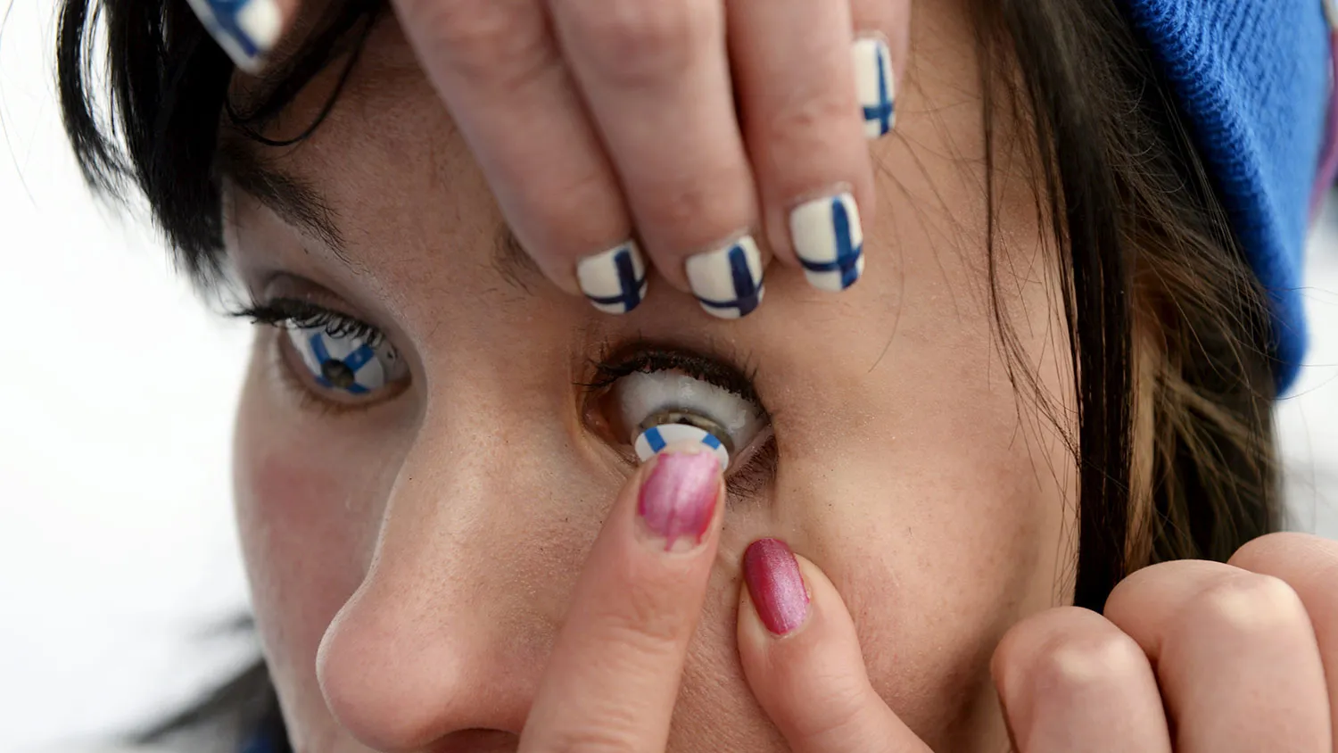 A Finnish ice hockey fan puts on contact lenses with the Finnish flag on May 3, 2013, in Helsinki.
