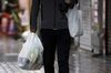 A man carries shopping bags as he walks down a street in Tokyo, Japan.