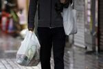 A man carries shopping bags as he walks down a street in Tokyo, Japan.