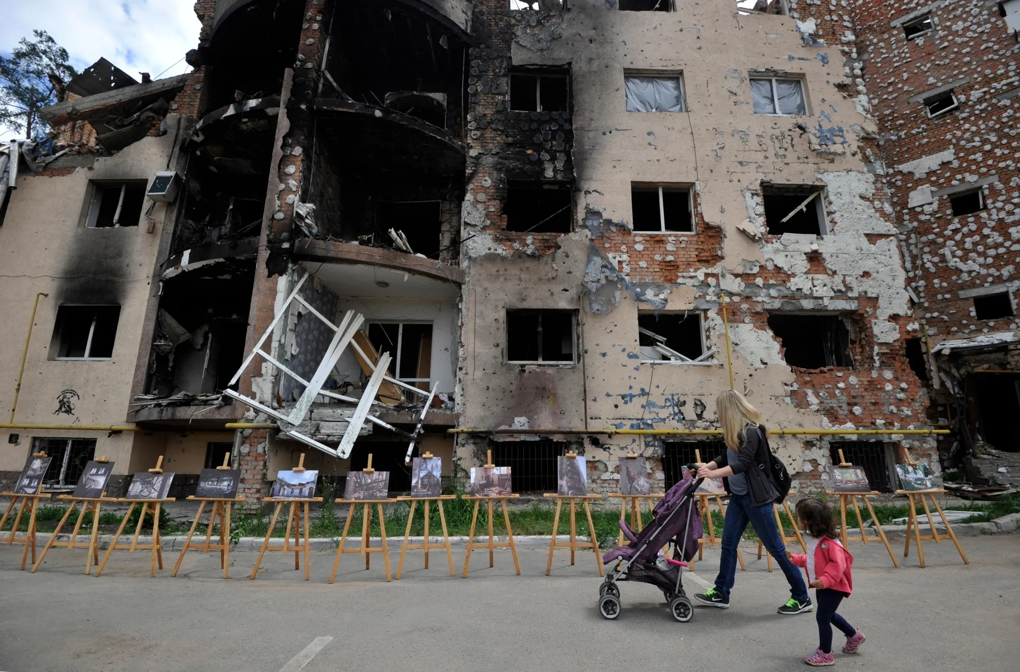 A woman and her daughter pass a destroyed&nbsp; residential building in Irpin, Ukraine.