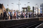 Rail passengers stand and wait for a train on a platform at Clapham Junction railway station in London, U.K., on Tuesday, Sept. 18, 2012. U.K. rail fares will jump as much as 6.2 percent in January, based on inflation figures released last month, with increments of more than 10 percent possible if train companies vary price changes, lobby group Passenger Focus said.
