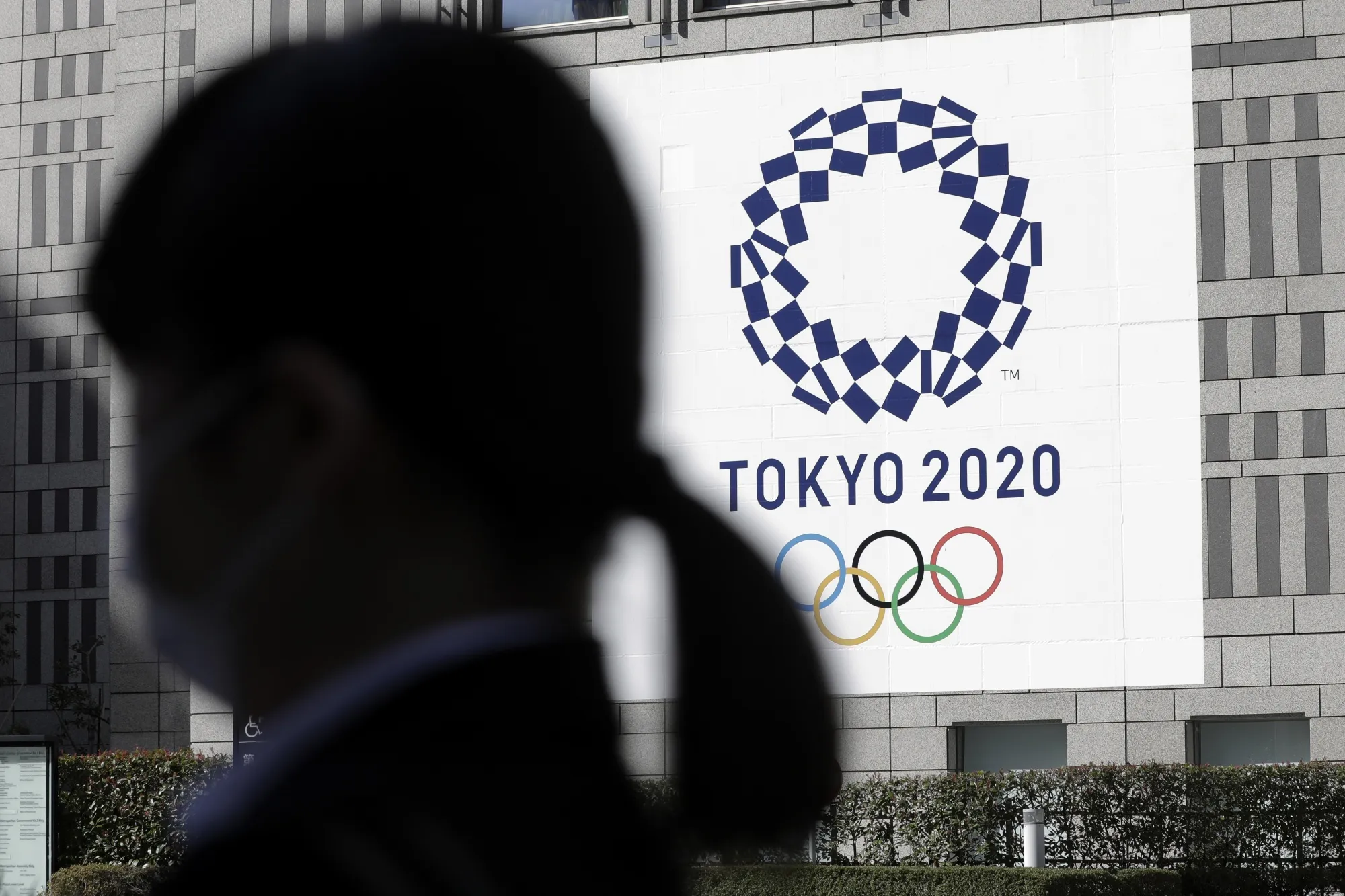 A pedestrian walks past a banner for the Tokyo 2020 Olympic Games.