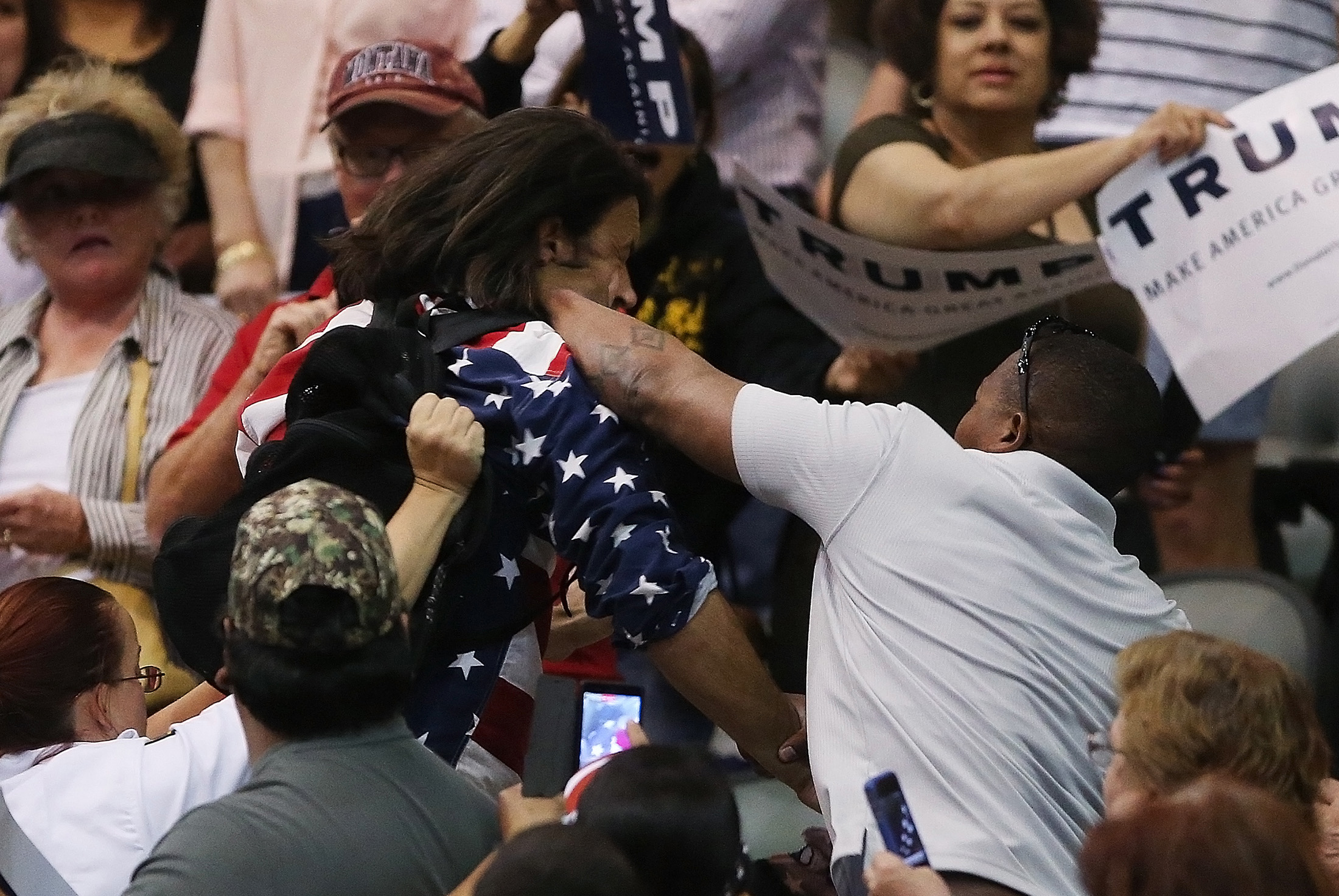 Trump protester Bryan Sanders, center left, is punched by a Trump supporter as he is escorted out of Republican presidential candidate Donald Trump's rally at the Tucson Arena in downtown Tucson, Ariz., Saturday, March 19, 2016. (Mike Christy/Arizona Daily Star via AP)
