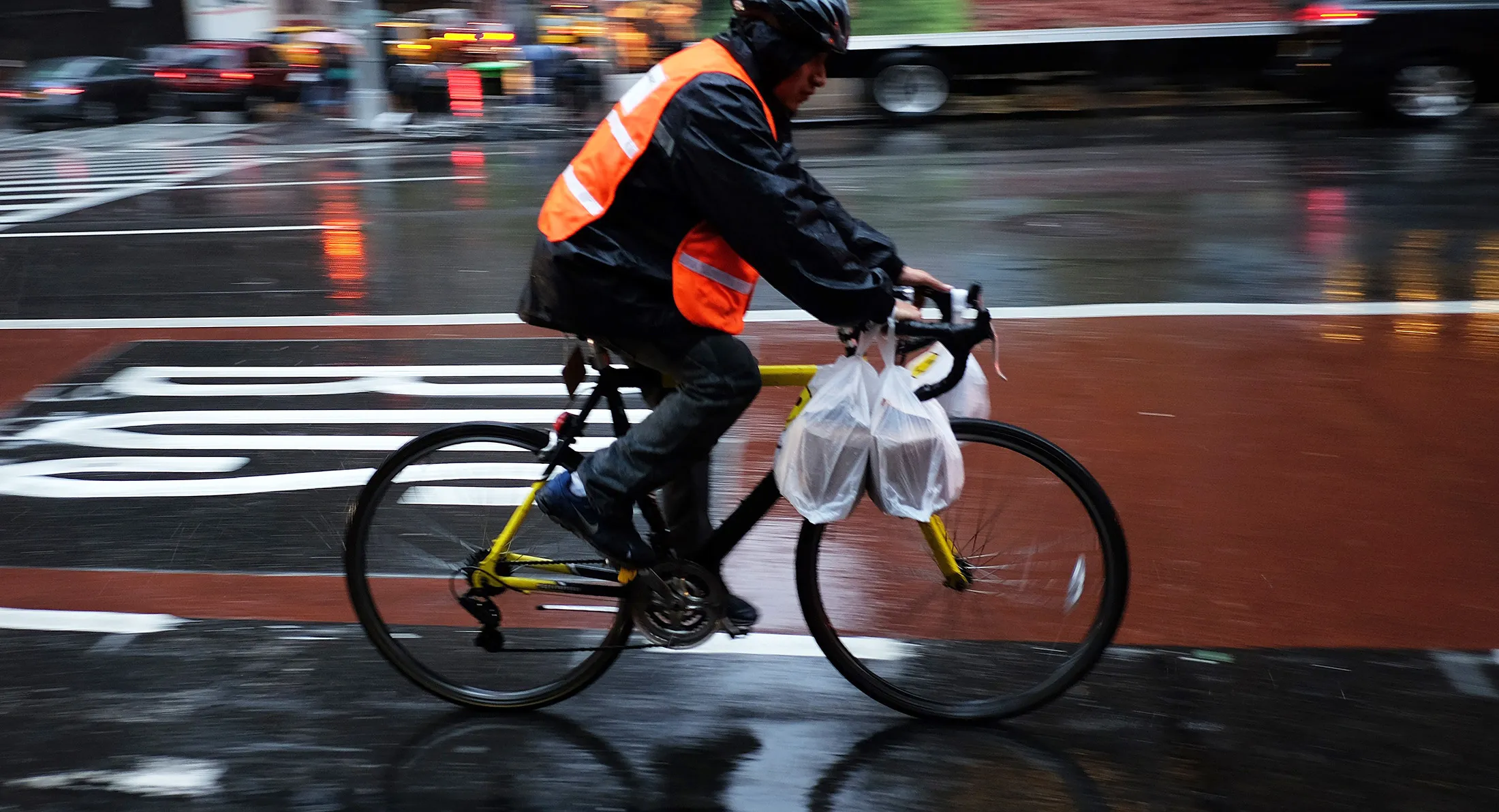 A delivery man rides his bike in the rain to deliver food in New York.
