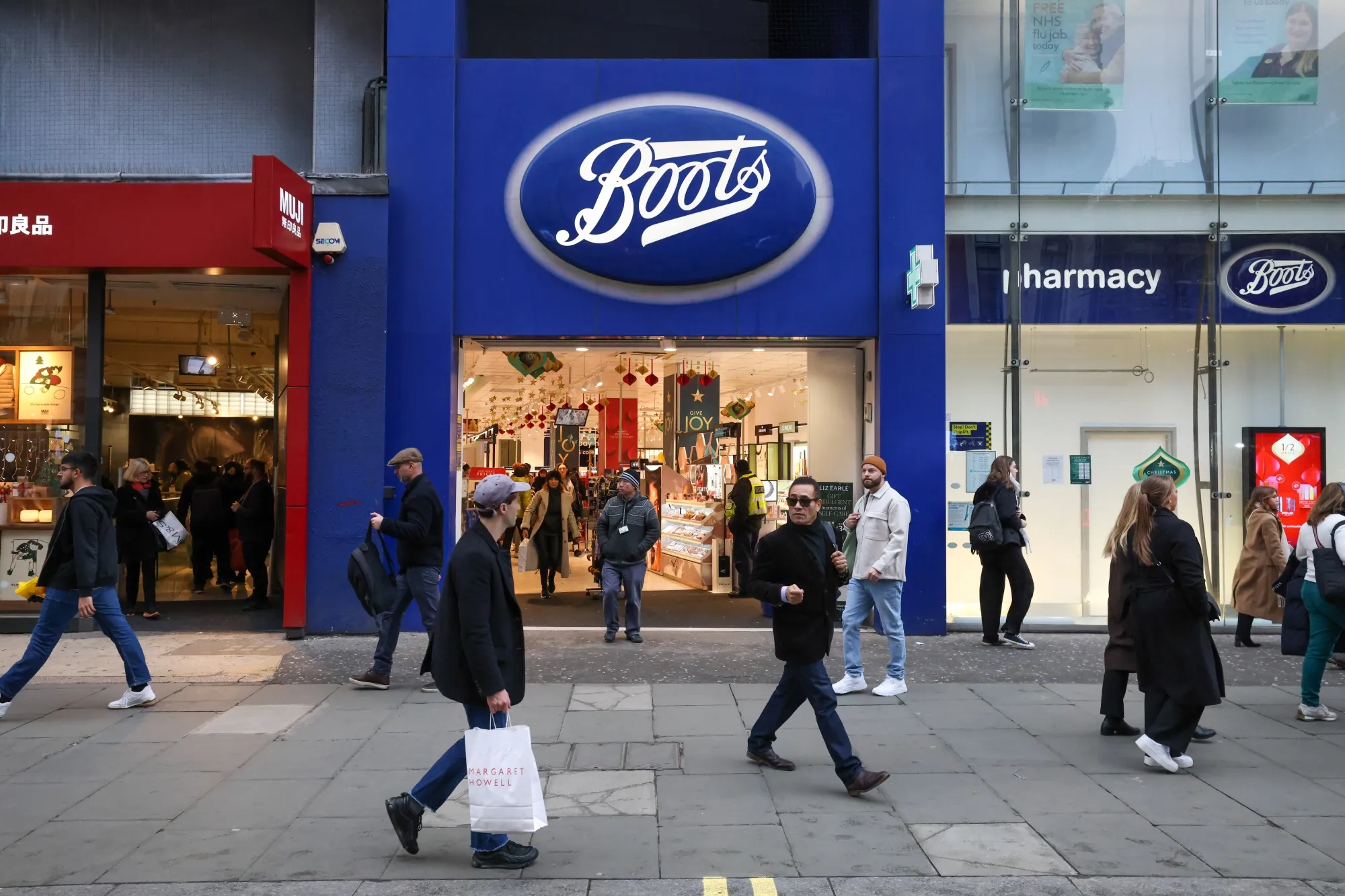 Pedestrians pass a Boots store in London.