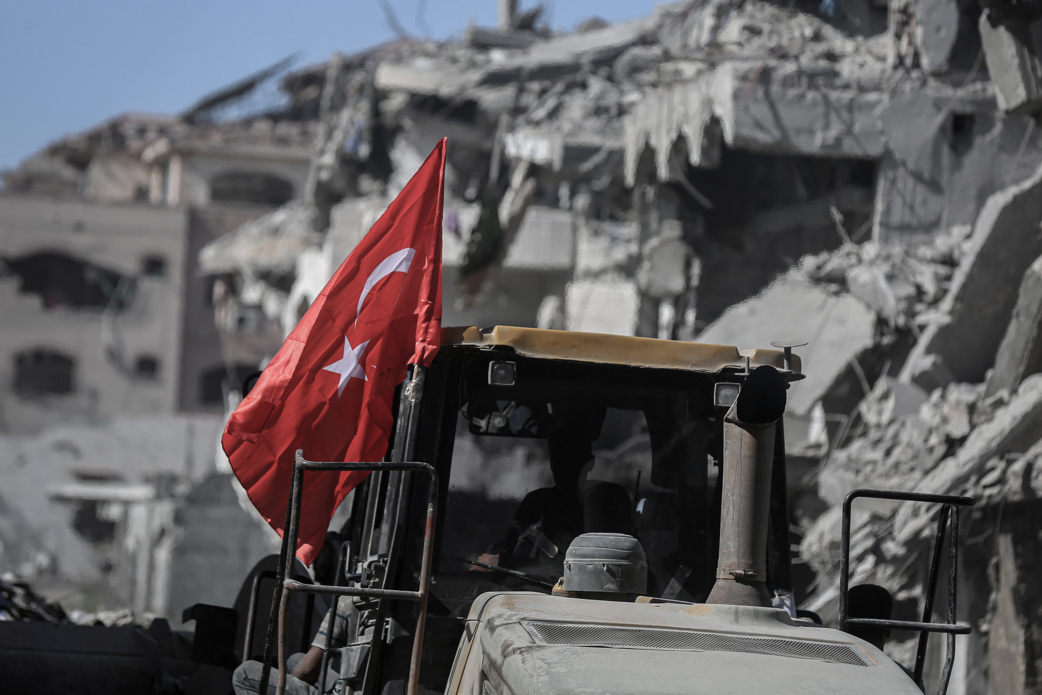 A Turkish flag flies from a bulldozer clearing rubble between destroyed buildings in Gaza City, Gaza, on Tuesday, Oct. 21, 2025. US Vice President JD Vance said he remains optimistic about the future of a ceasefire between Israel and Hamas despite a flareup in violence over the weekend, part of a bid to keep talks progressing on the future of Gaza. Photographer: Ahmad Salem&#x2F;Bloomberg