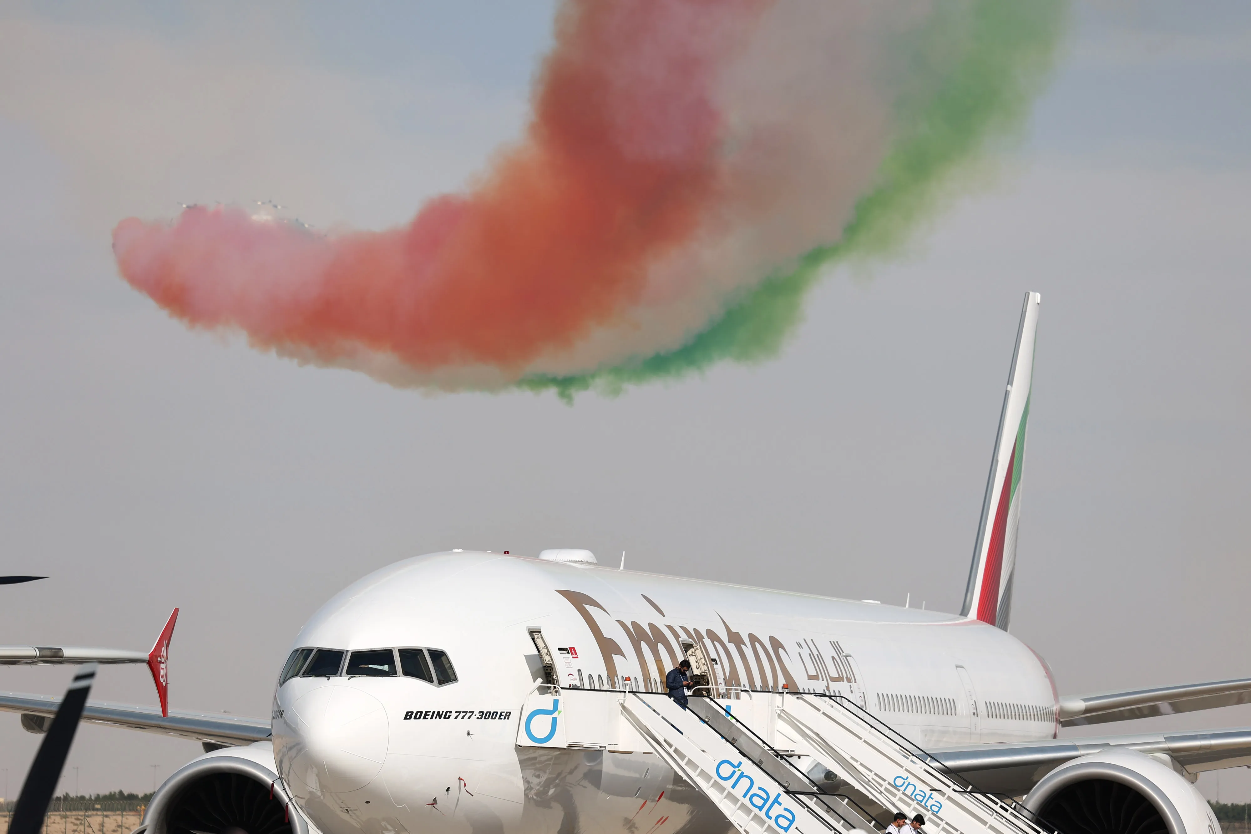 The Al Fursan UAE Air Force aerobatic display team perform above a Boeing Co. 777-300ER passenger aircraft, operated by Emirates Airlines, at the Dubai Air Show.