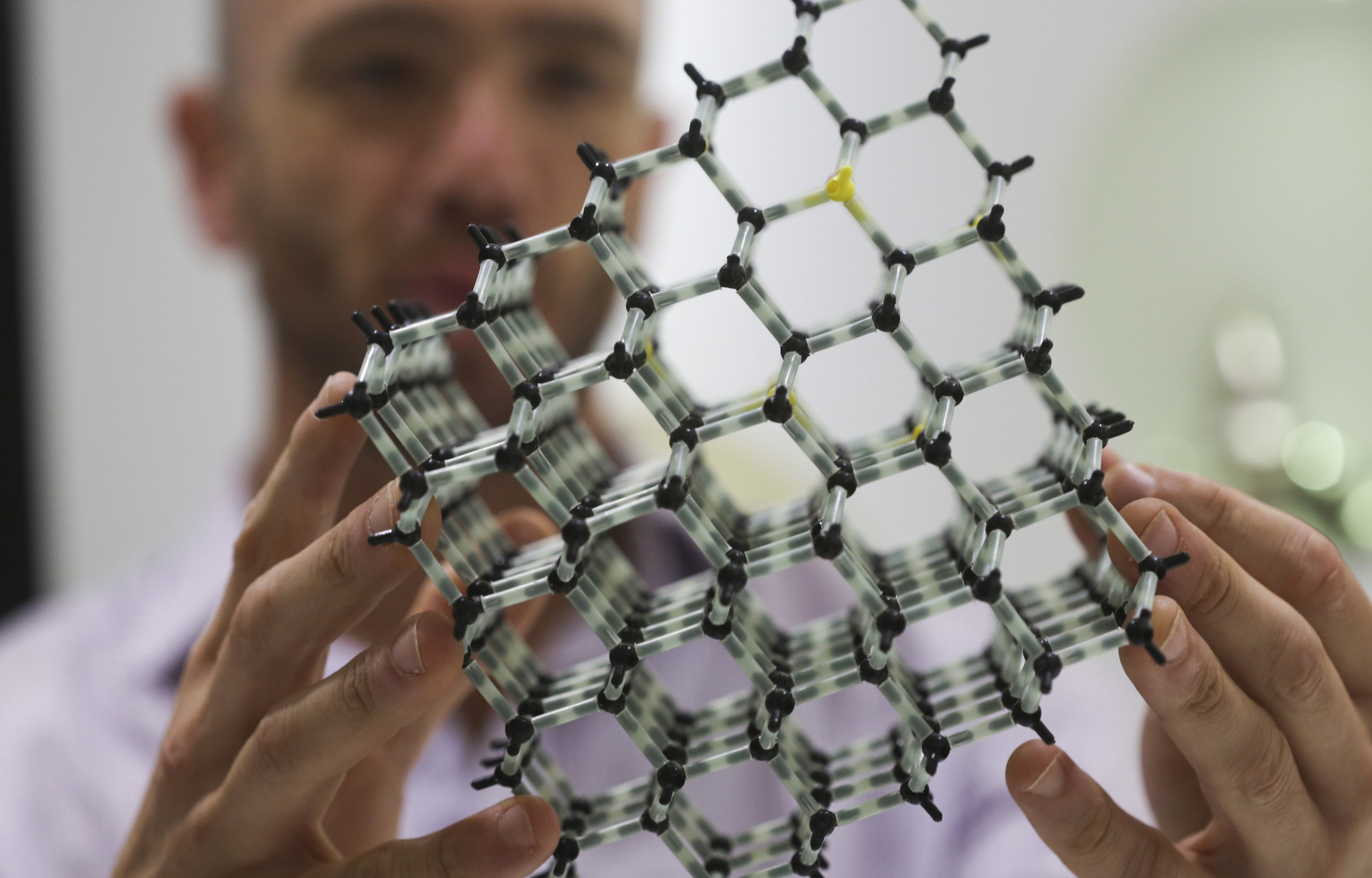 An employee at Element Six holds a molecular structure model of a diamond.
