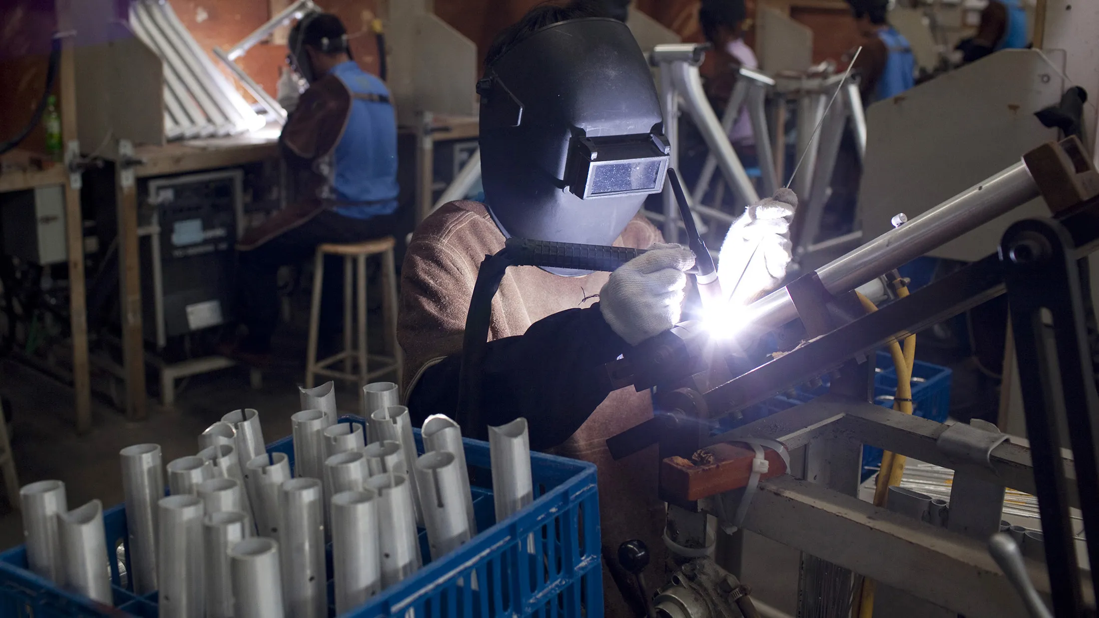 An employee welds metalwork for bicycles.
