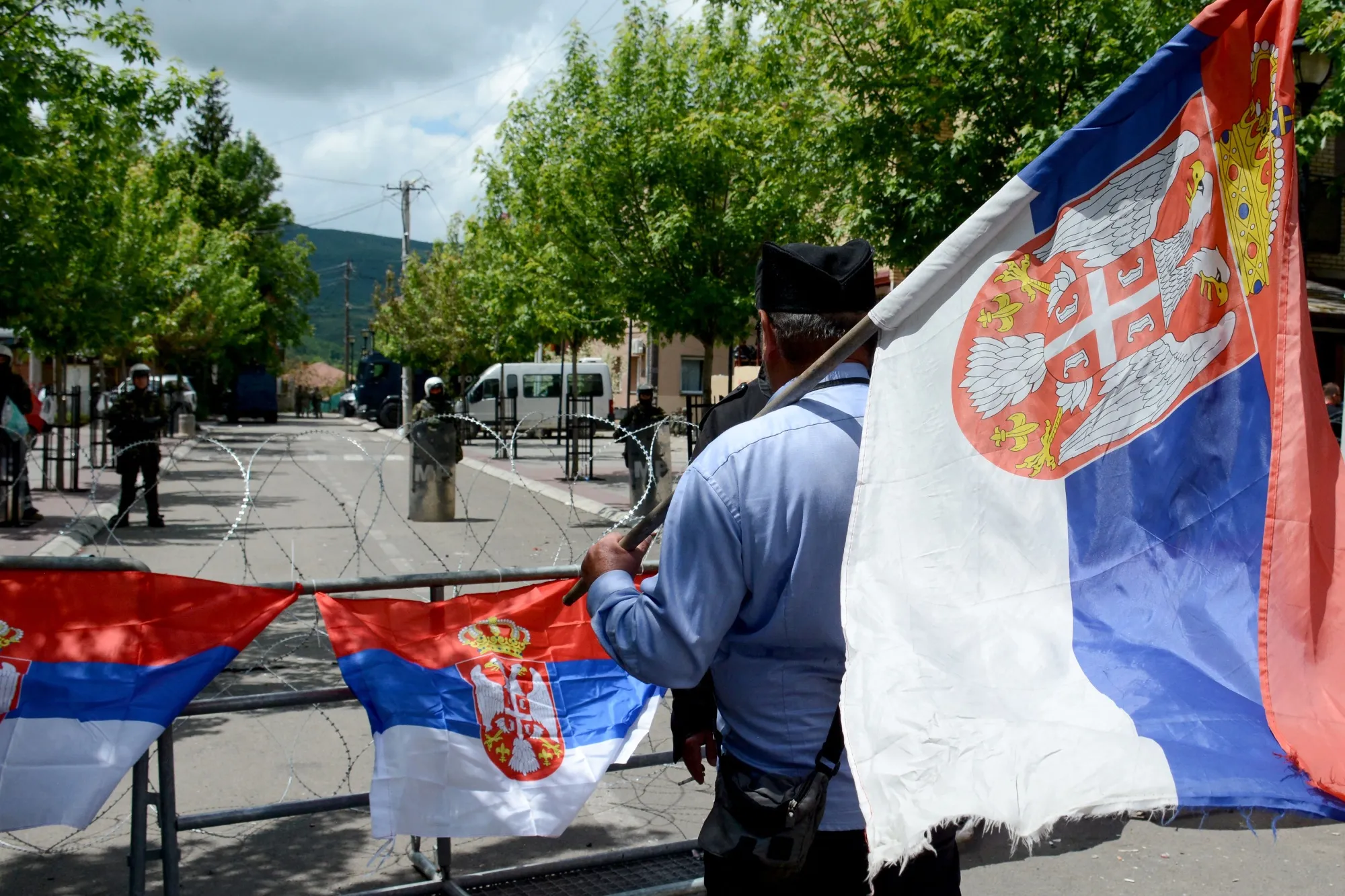 A man holding a Serbian flag stands near&nbsp;Kosovo Force soldiers in Zvecan, Kosovo in May 2023.
