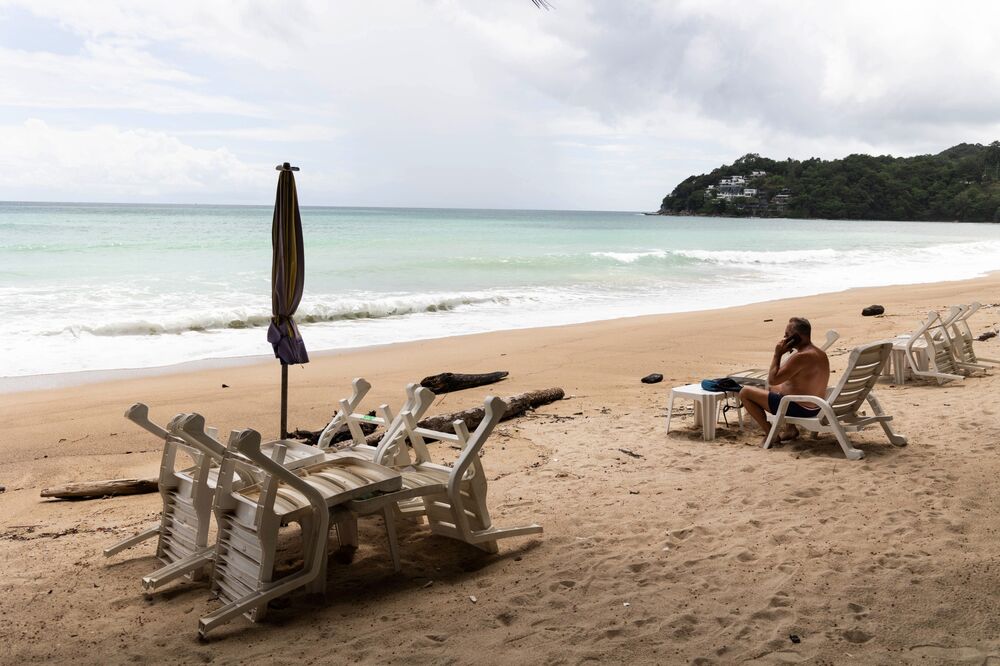 A beach-goer sits next to lounge chairs stacked on Kamala beach in Phuket on June 26.
