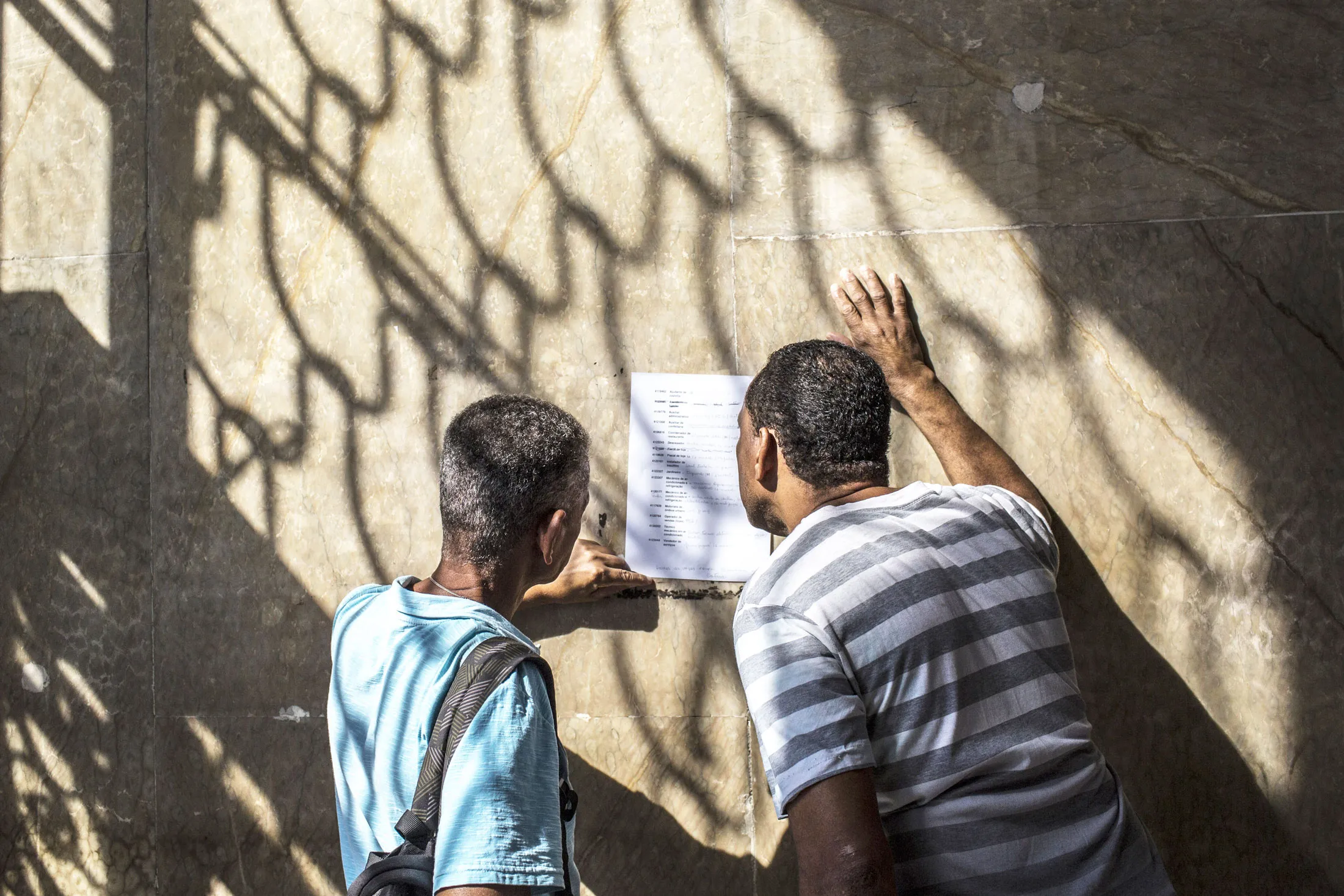 Job seekers view a list of employment openings outside the Ministry of Labor and Employment in Rio de Janeiro.
