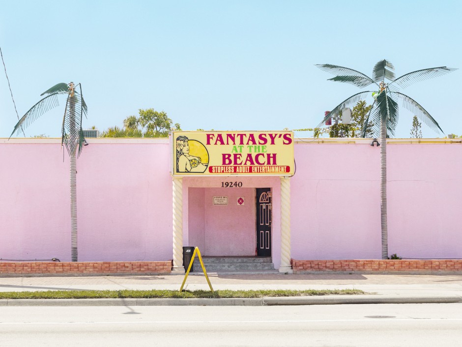 Fake palm trees and a candy-pink, windowless exterior at a Florida strip club.