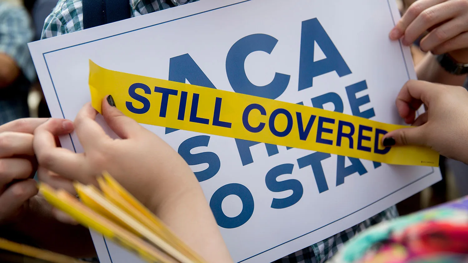 A demonstrator places a sticker on a sign after the U.S. Supreme Court ruled to save Obamacare tax subsidies in Washington on June 25, 2015.
