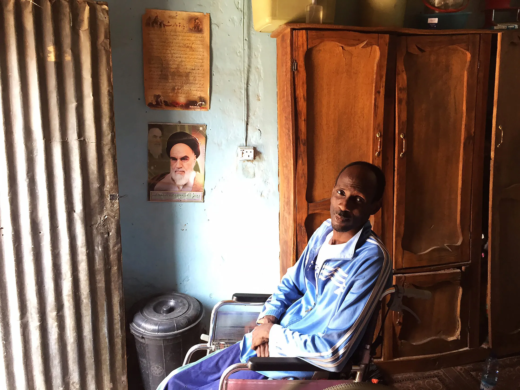 Former newspaper vendor Sharif Abu Bakr Zakariya sits in his wheelchair at home in the northern town of&nbsp;Kano on Feb. 10 as&nbsp;Iran's first Supreme Leader Ayatollah Ruhollah Khomeini looks on.&nbsp;
