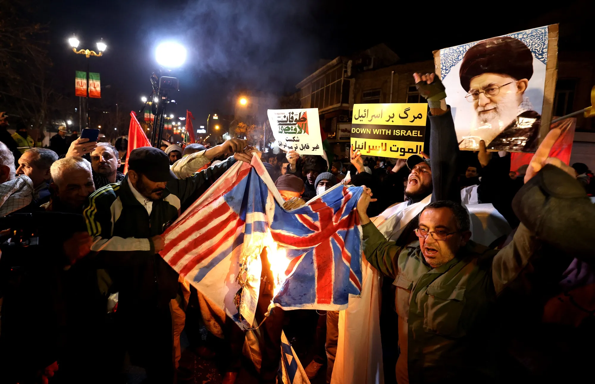 Iranian protesters burn a Union Jack flag and a US flag during a demonstration in solidarity with the Palestinian people and Iran-backed Yemeni rebels.