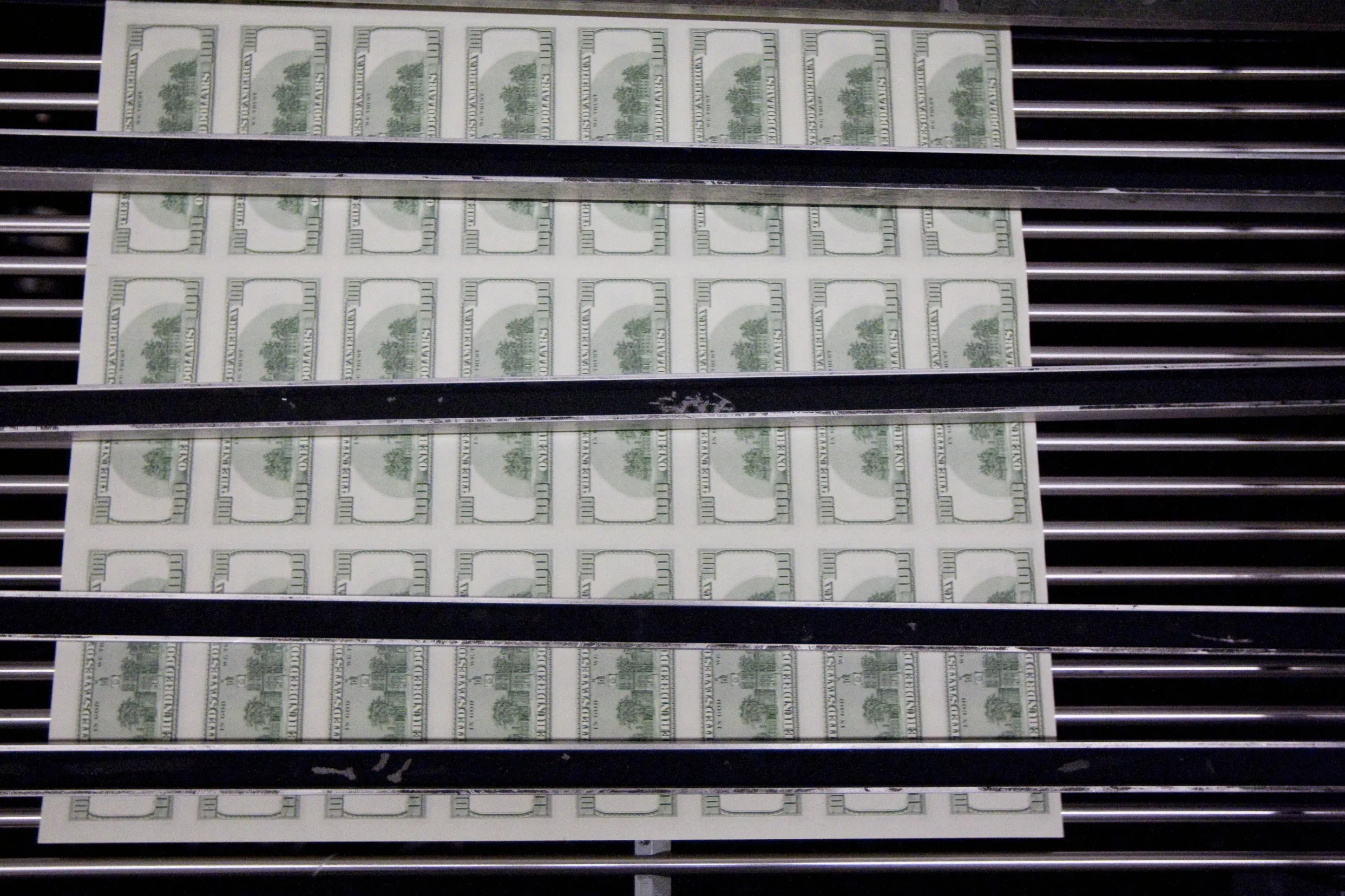 Sheets of one hundred dollar bills are fed through a sorting machine at the Bureau of Engraving and Printing in Washington, D.C., U.S., on Wednesday, Oct. 14, 2009. Goldman Sachs Group Inc. said the dollar is likely to extend drops against the euro and commodity backed currencies over the coming six months, based on the greenback's correlation with cyclical assets and capital flows.