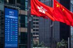 The flags of China, right, and the Hong Kong Special Administrative Region (HKSAR) fly near an electronic screen displaying stock figures.