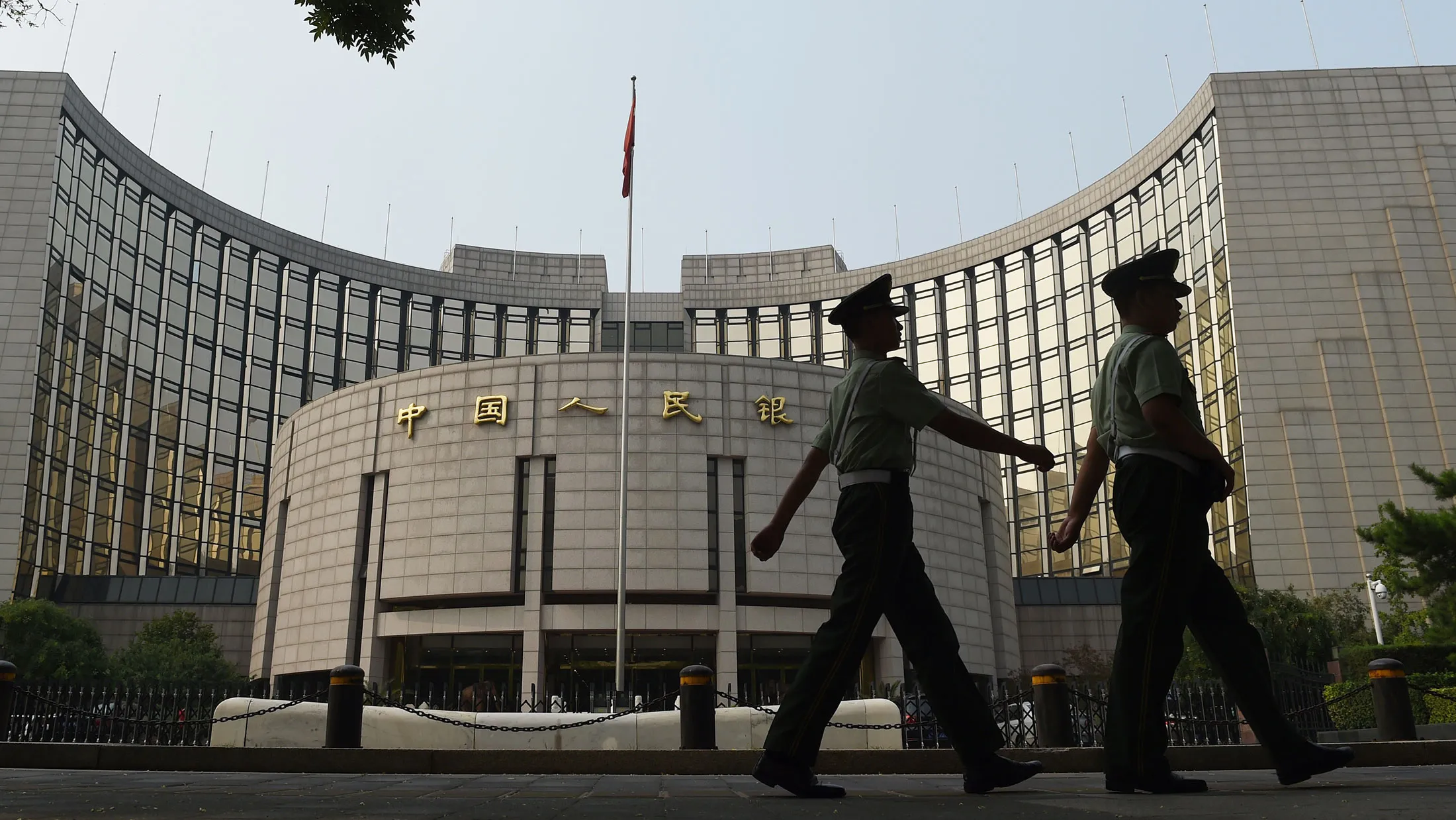 Paramilitary policemen patrol in front of the People's Bank of China in Beijing. China’s central bank will impose required reserve ratios on yuan deposits of offshore participant banks in the mainland in a bid to stabilize the currency.
