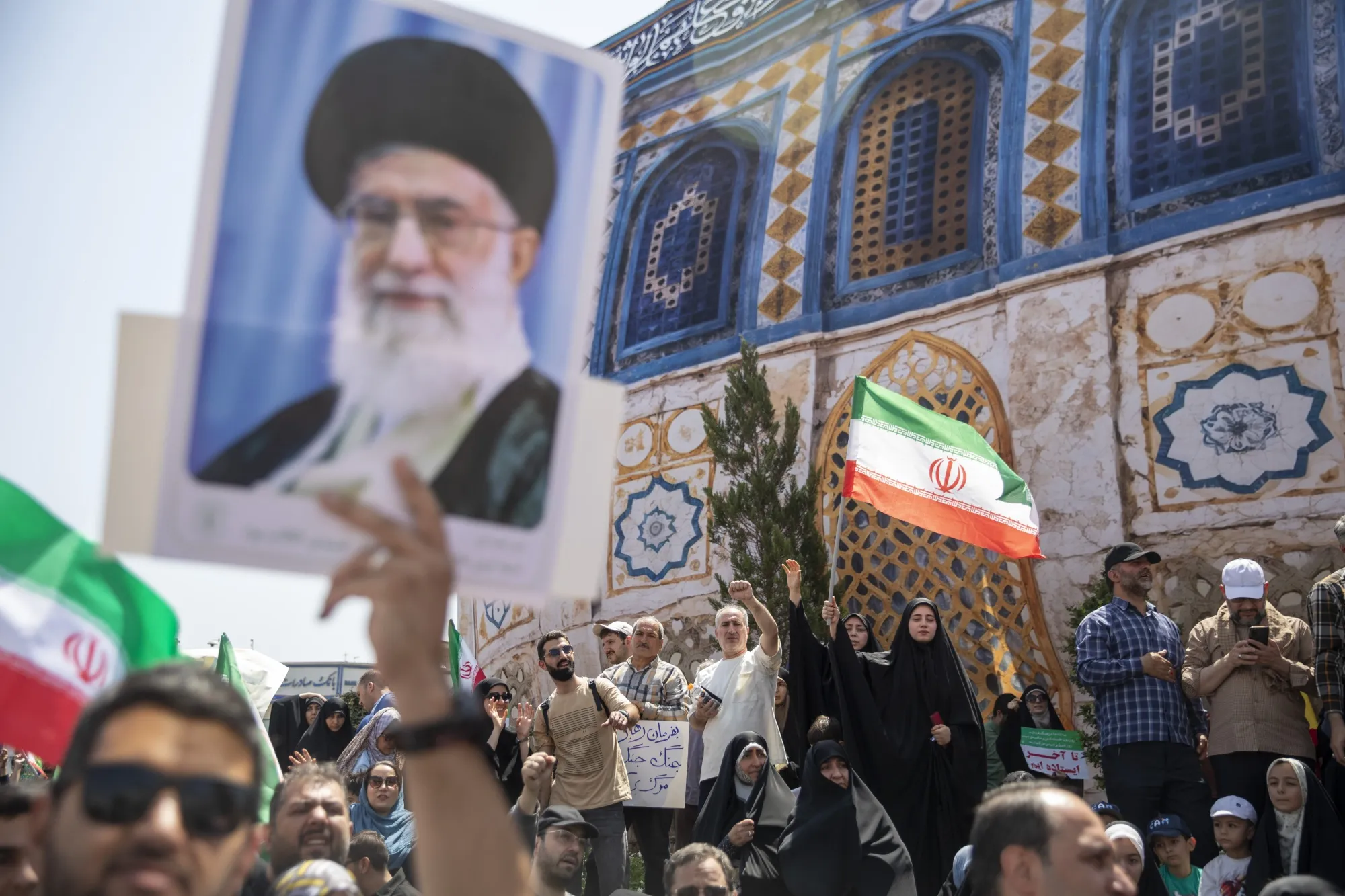 TEHRAN, IRAN - JUNE 20: Demonstrators wave Iranian flags as one holds up a poster of Iran's Supreme Leader Ayatollah Ali Khamenei during a protest against Israeli attacks on Iran, after the Friday prayer ceremonies on June 20, 2025 in central Tehran, Iran.