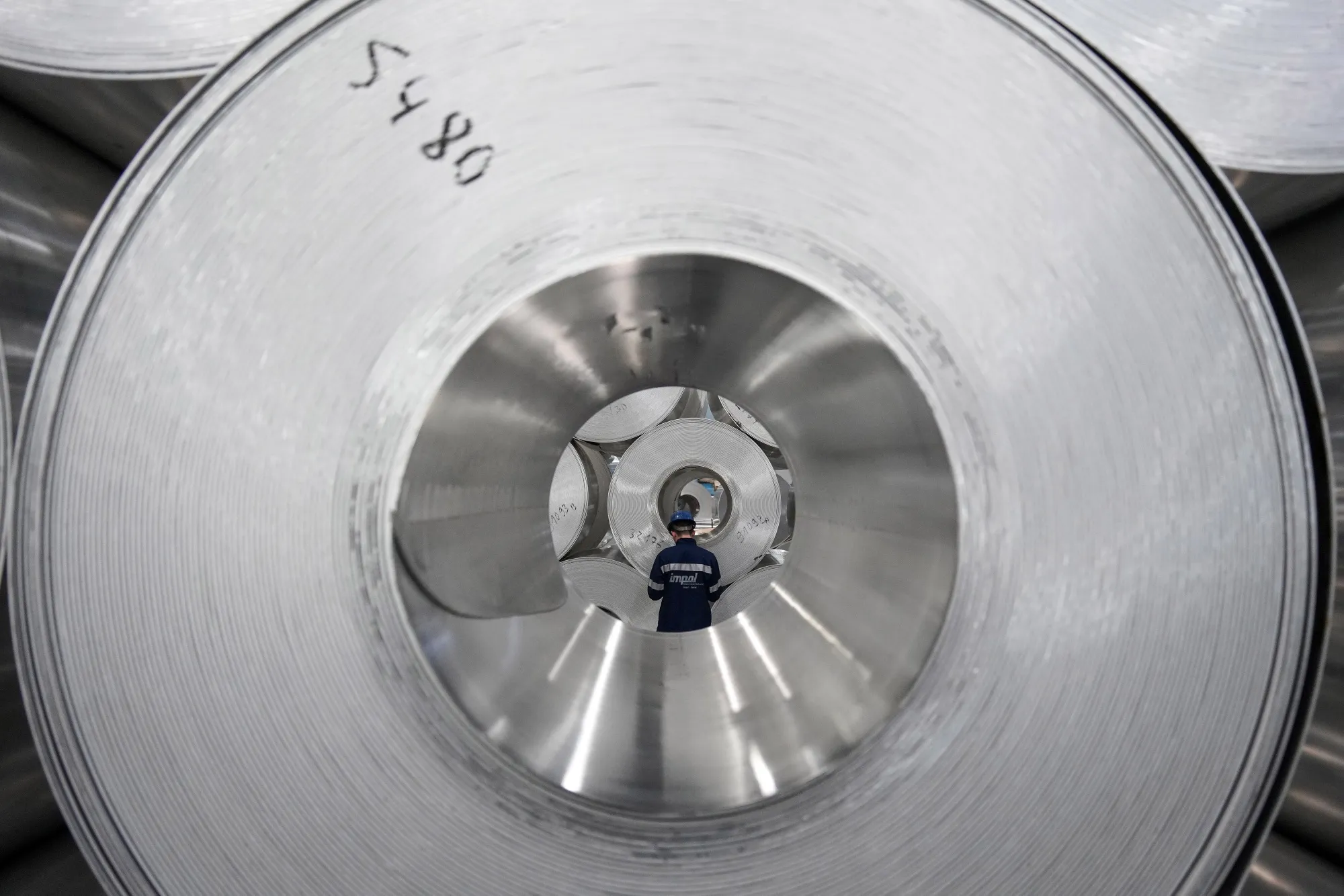 A worker checks the inventory of rolls of sheet aluminum.