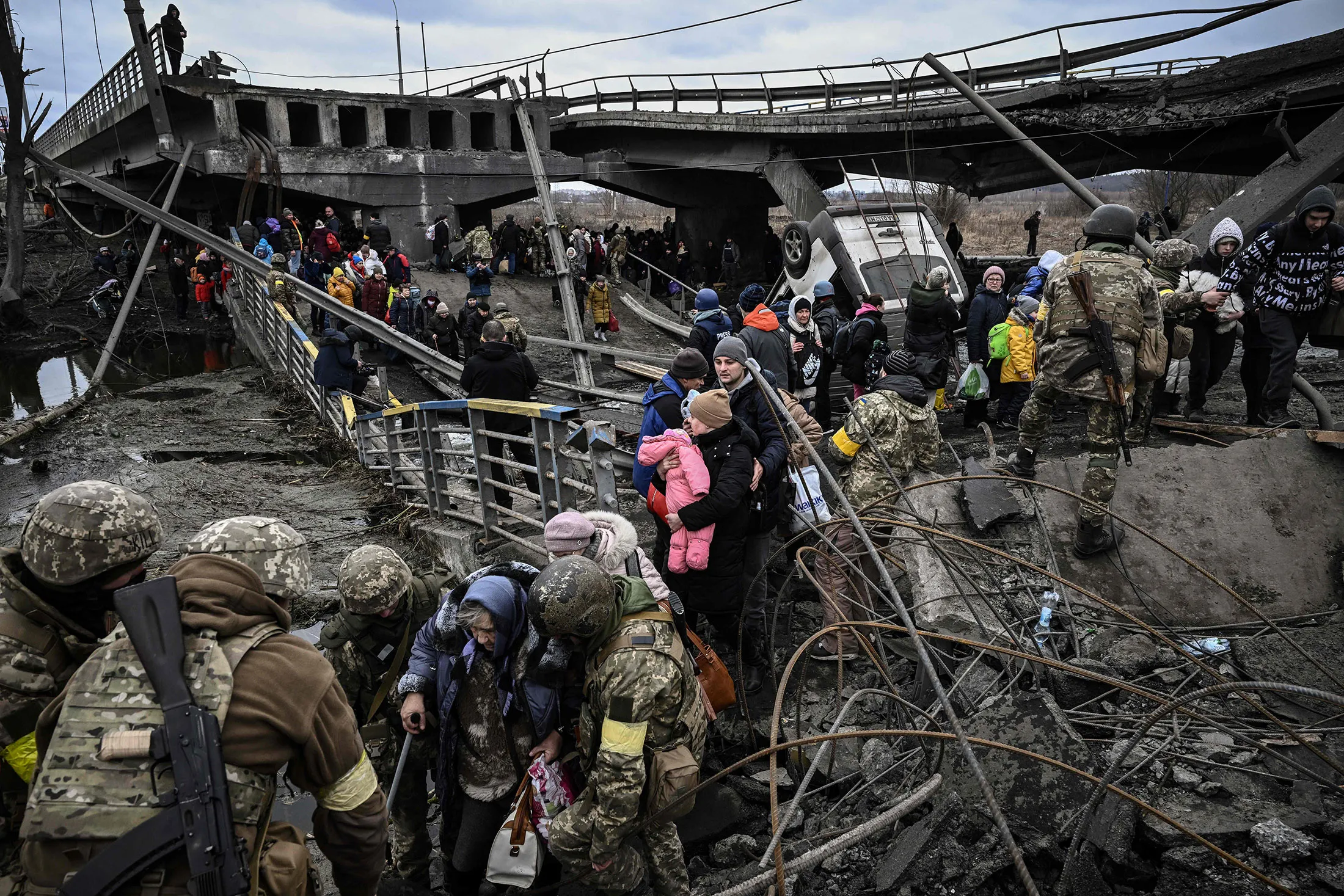 Residents cross a destroyed bridge as they evacuate the city of Irpin, northwest of Kyiv,&nbsp;on March 5.